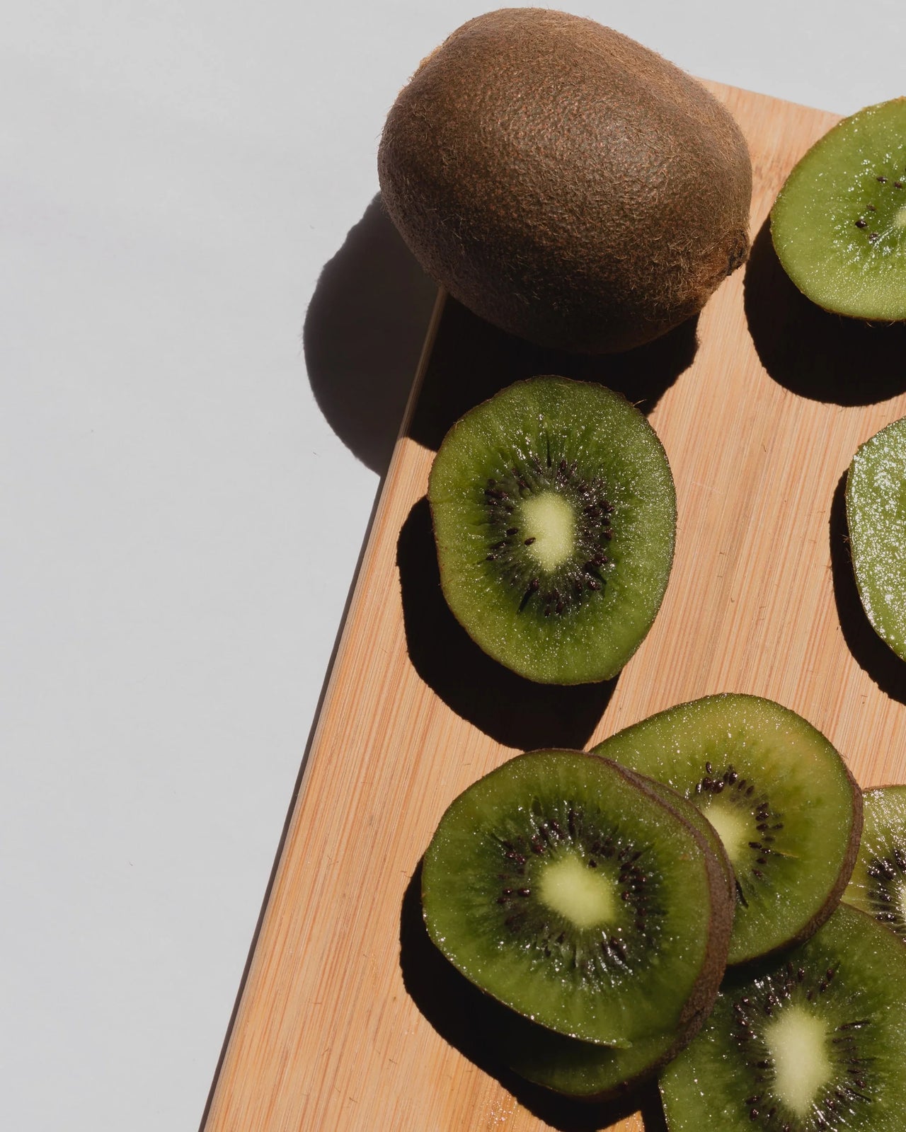 Sliced and whole kiwis on a cutting board